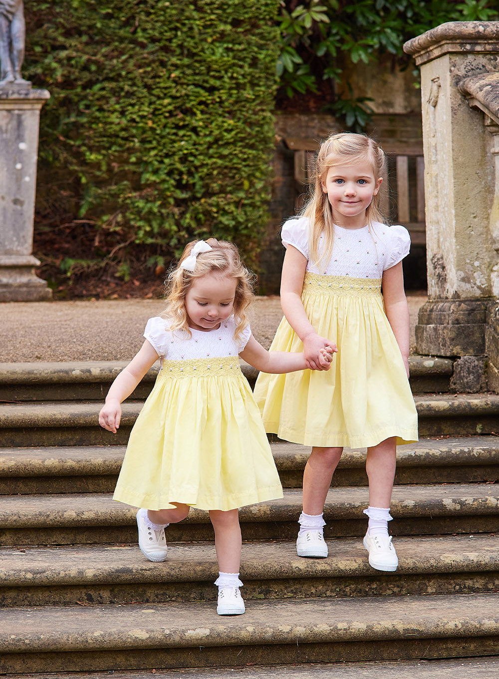 Girls Rose Hand Smocked Dress in Lemon Yellow | Trotters Trotters Childrenswear Girls Rose Hand Smocked Dress in Lemon Yellow | Trotters Trotters Childrenswear